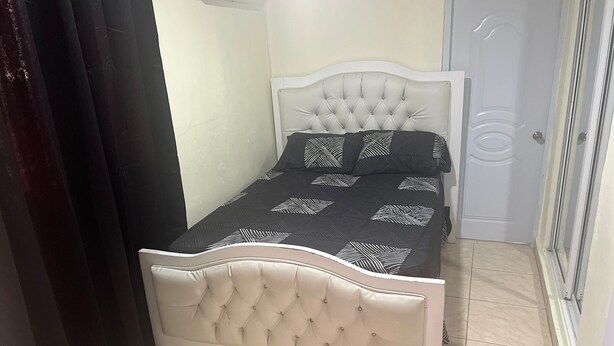 Una cama con cabecera capitonada y colcha estampada.