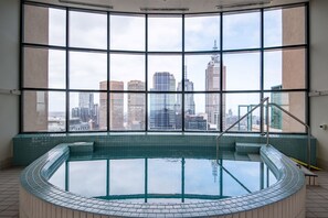 Een modern overdekt zwembad met een panoramisch stadsgezicht door grote ramen.