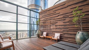 A modern lounge with wooden flooring, a slatted wall, and a view of a cityscape. - Elegant 4B 2B Unit in Melbourne CBD w/ Parking! (Melbourne)