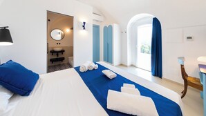 A hotel room with a large bed, a bathroom, and a view of the outdoors. - Villa Maiuri by MyVillaCollection (Anacapri)