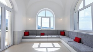 A spacious room with a large arched window, a built-in bench with red cushions, and a view of the outdoors. - Villa Maiuri by MyVillaCollection (Anacapri)