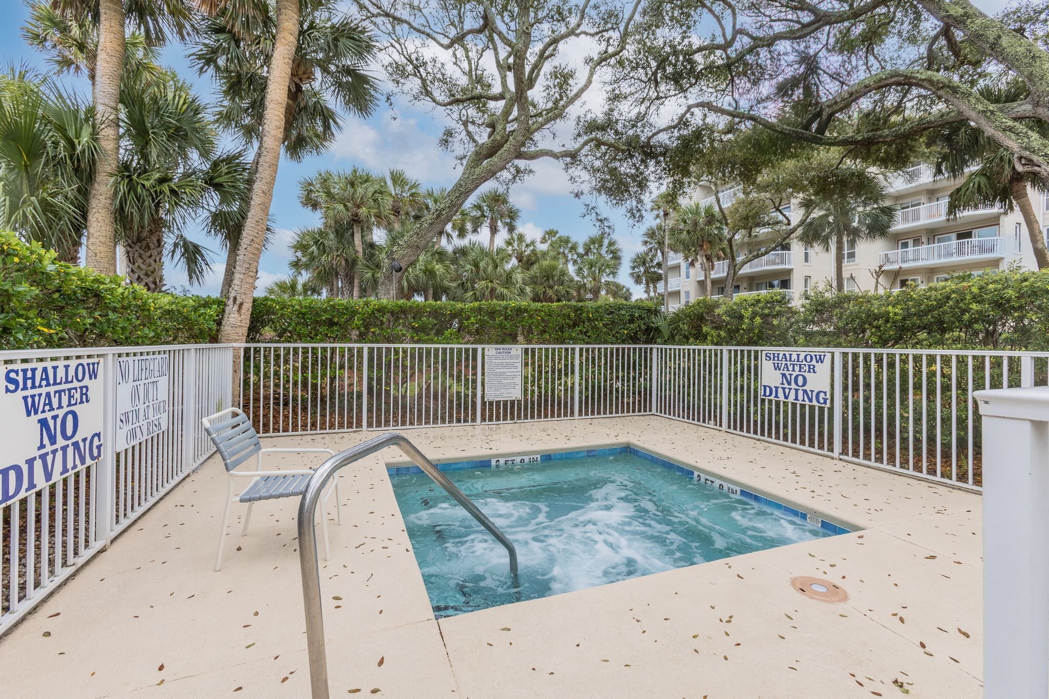 A pool area with a sign warning about shallow water and no diving.