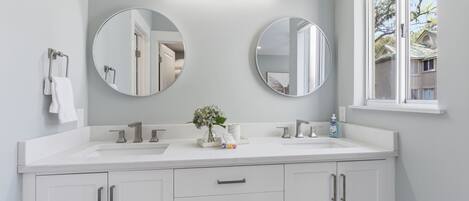 A bathroom with two sinks, a mirror, a towel rack, and a window.