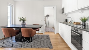 Et moderne køkken med hvide skabe, en sort bordplade og en indbygget ovn.