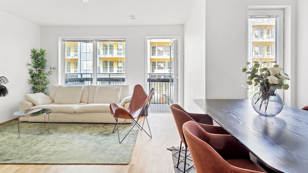 En moderne stue med sofa, spisebord med stole, sofabord og en potteplante.