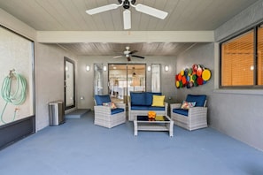 A covered outdoor seating area with wicker furniture, ceiling fans, and a wall art installation. - Florida Haven 4/2.5 Vacation Ready Home! Book Now! (Seminole)