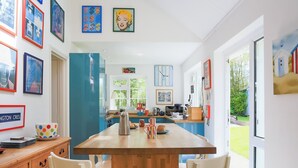 A modern kitchen with a wooden island, white chairs, and various kitchen appliances. - 4 bedroom accommodation in Rock (Rock)
