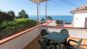A balcony with a table and chairs, overlooking a coastal view with a clear sky. - Orizzonte Blu Superior 11, Palinuro, Cilento (Palinuro)