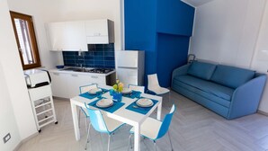 A compact living space with a kitchenette, dining area, and a blue sofa. - Orizzonte Blu Superior 11, Palinuro, Cilento (Palinuro)