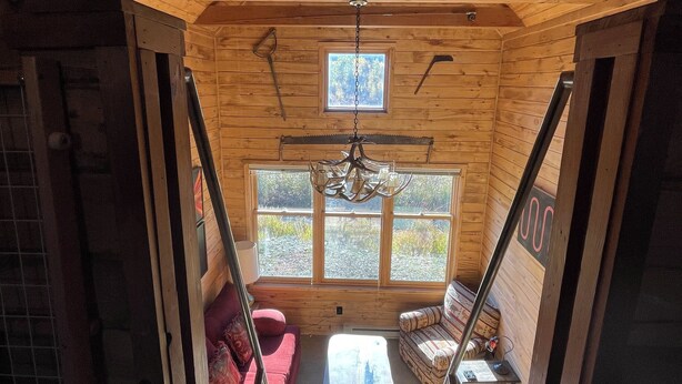 L’intérieur d’un chalet en bois, avec un lit en mezzanine, un canapé rouge et une petite table.