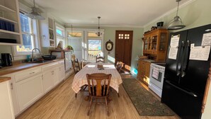 Une cuisine spacieuse avec des meubles de rangement en bois, une table à manger avec des chaises, un réfrigérateur et une fenêtre donnant sur l’extérieur.