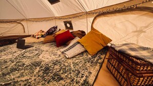L'intérieur d'une tente, avec un ordinateur portable, des coussins et un panier en osier.