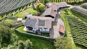 Una casa de campo moderna con paneles solares, rodeada de campos verdes exuberantes y una pequeña iglesia.