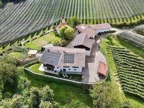 Een moderne boerderij met zonnepanelen, omringd door weelderige groene velden en een kleine kerk.