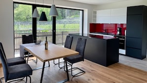 Una cocina moderna con comedor, ventanas amplias y vistas a zonas verdes.