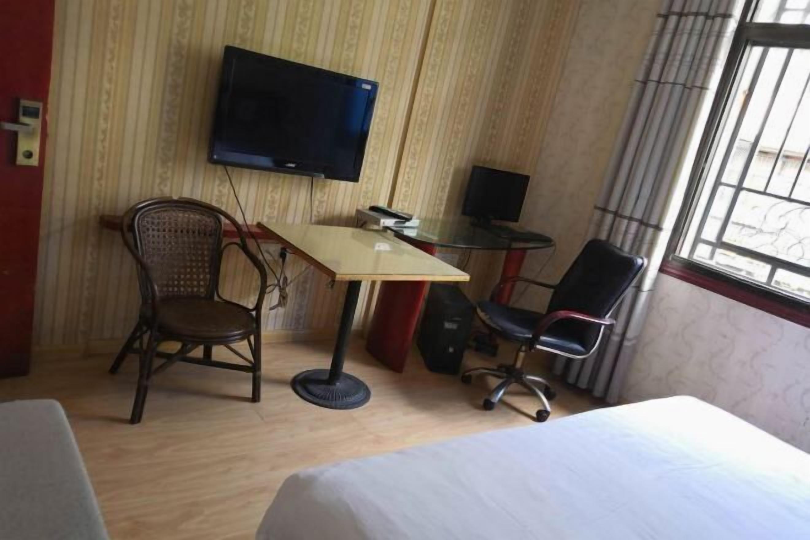 A hotel room with a bed, two chairs, a desk, a television, and a window.