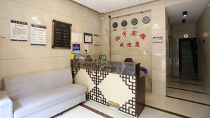 Un espace d’accueil comprenant un canapé, un comptoir de réception au motif décoratif et un mur orné d’horloges et de panneaux indicateurs.