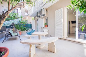 Uma área de estar ao ar livre com um balanço, uma mesa redonda e um vaso de planta.