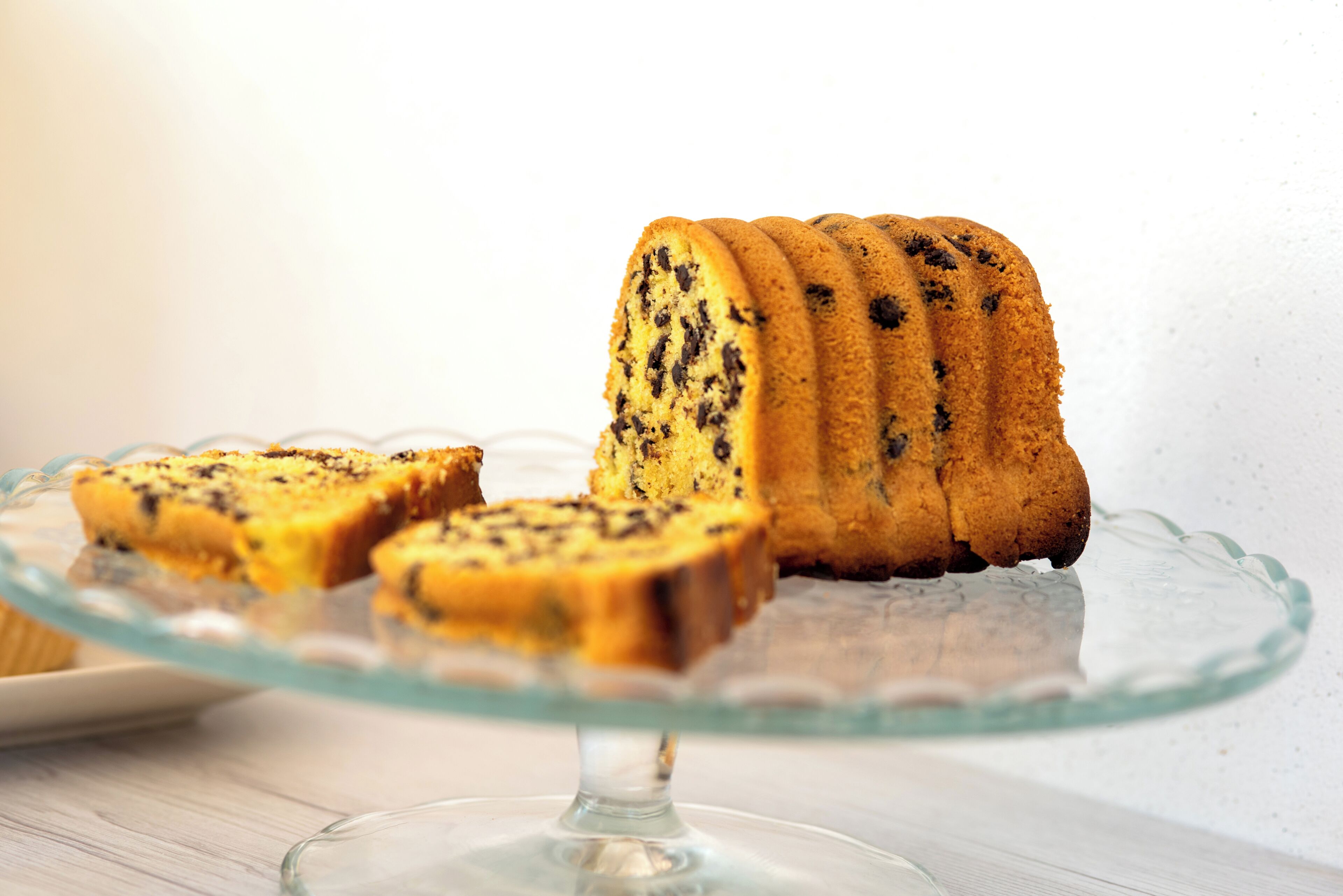 Un gâteau en forme de couronne, présenté sur un présentoir à gâteaux en verre.
