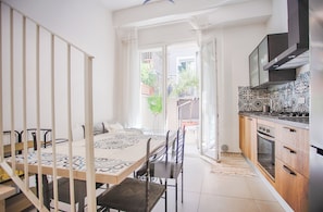 A kitchen with a tiled backsplash, a dining area with a patterned table, and a view of the outside. - B&B Fontanella32  (Porto Sant'Elpidio)