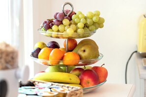 A three-tiered fruit stand with various fruits and a mug. - B&B Fontanella32 (Porto Sant'Elpidio)