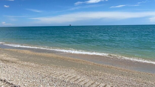 A beach with a pebbly shore and calm sea.