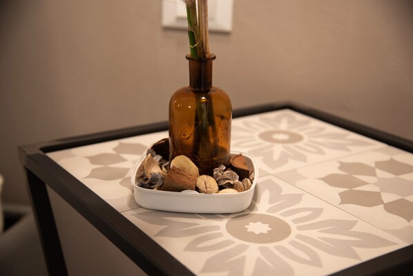A decorative arrangement with a brown bottle, a plant, and various stones on a patterned table. - B&B Fontanella32  (Porto Sant'Elpidio)