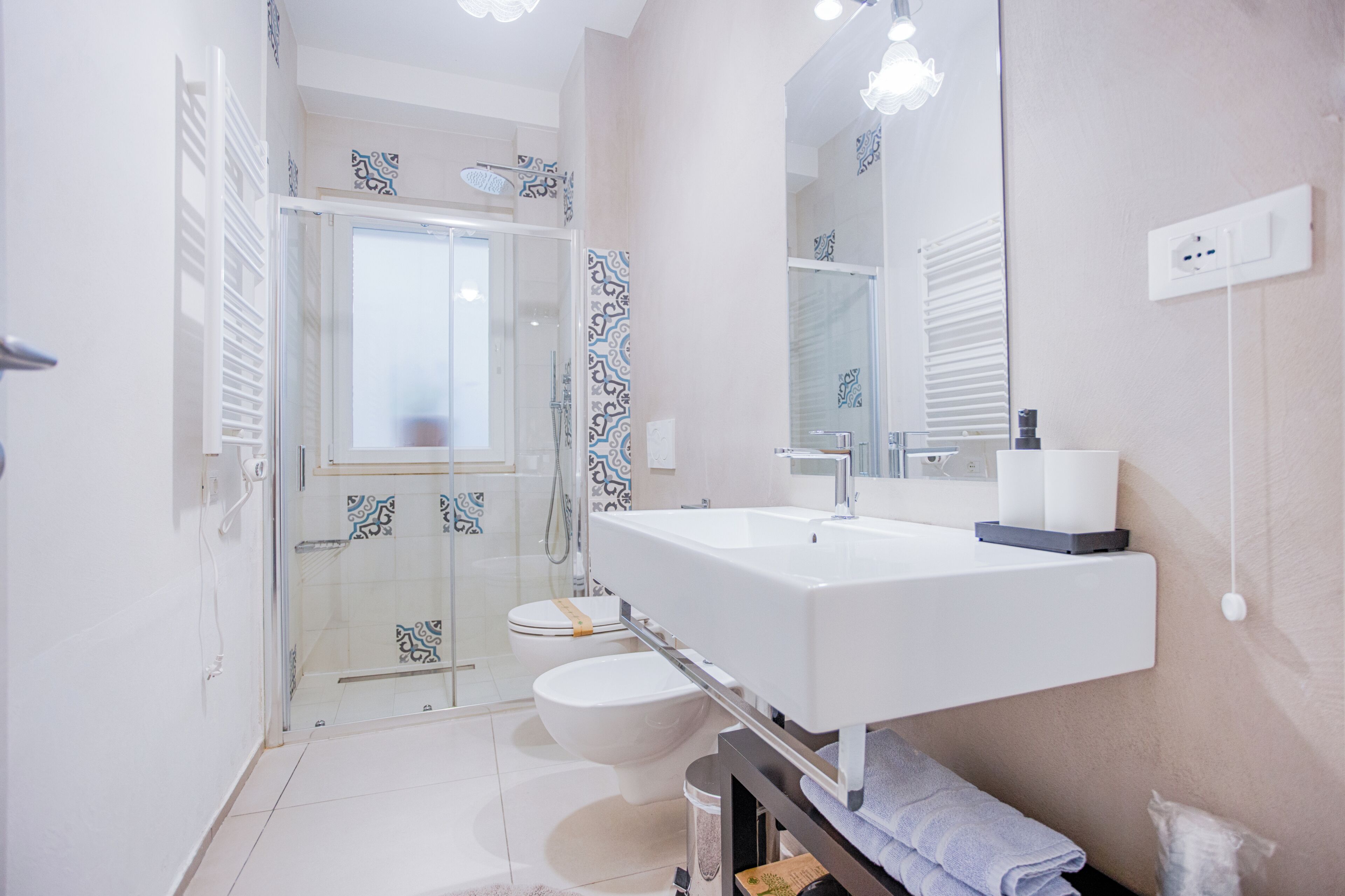 A modern bathroom with a glass shower enclosure, a white sink, and a large mirror.