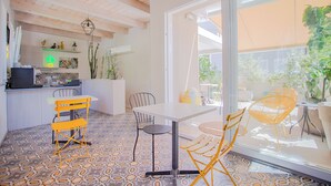 A modern interior with a kitchen area, dining table, chairs, and a large glass door leading to an outdoor space.