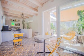 A modern interior with a kitchen area, dining table, chairs, and a large glass door leading to an outdoor space. - B&B Fontanella32  (Porto Sant'Elpidio)