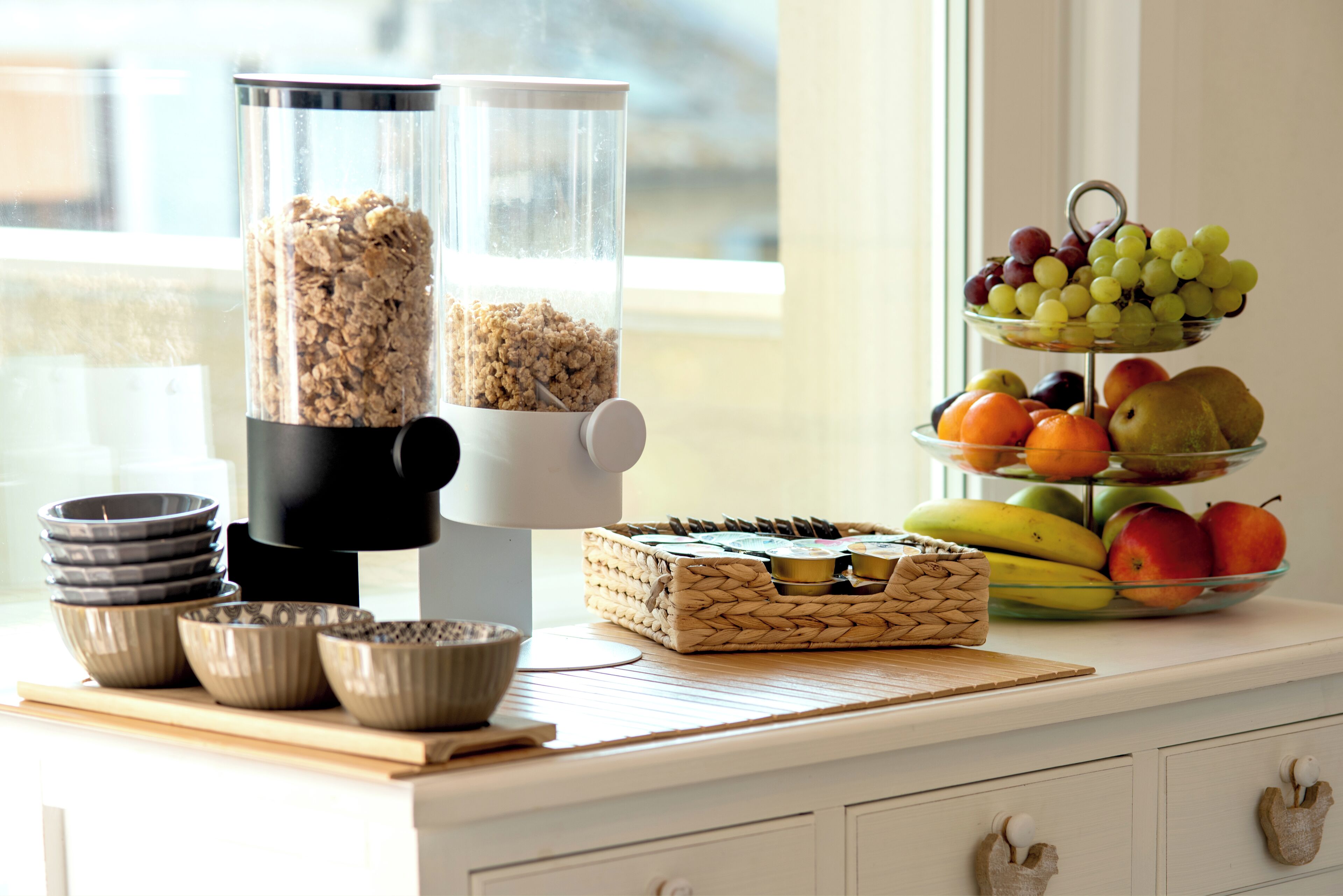 A kitchen counter with a food processor, bowls, a woven basket, and a fruit display.
