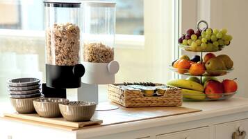 A kitchen counter with a food processor, bowls, a woven basket, and a fruit display.