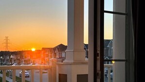 Varanda com vista para uma rua residencial ao pôr do sol.
