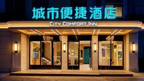 L’extérieur du City Comfort Inn se distingue par sa façade moderne, son enseigne lumineuse, son entrée accueillante et l’éclairage intérieur visible.