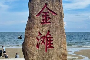 A large rock with Chinese characters, a beach, and the ocean in the background. - City Comfort Inn (Dongxing Port) (Dongxing)