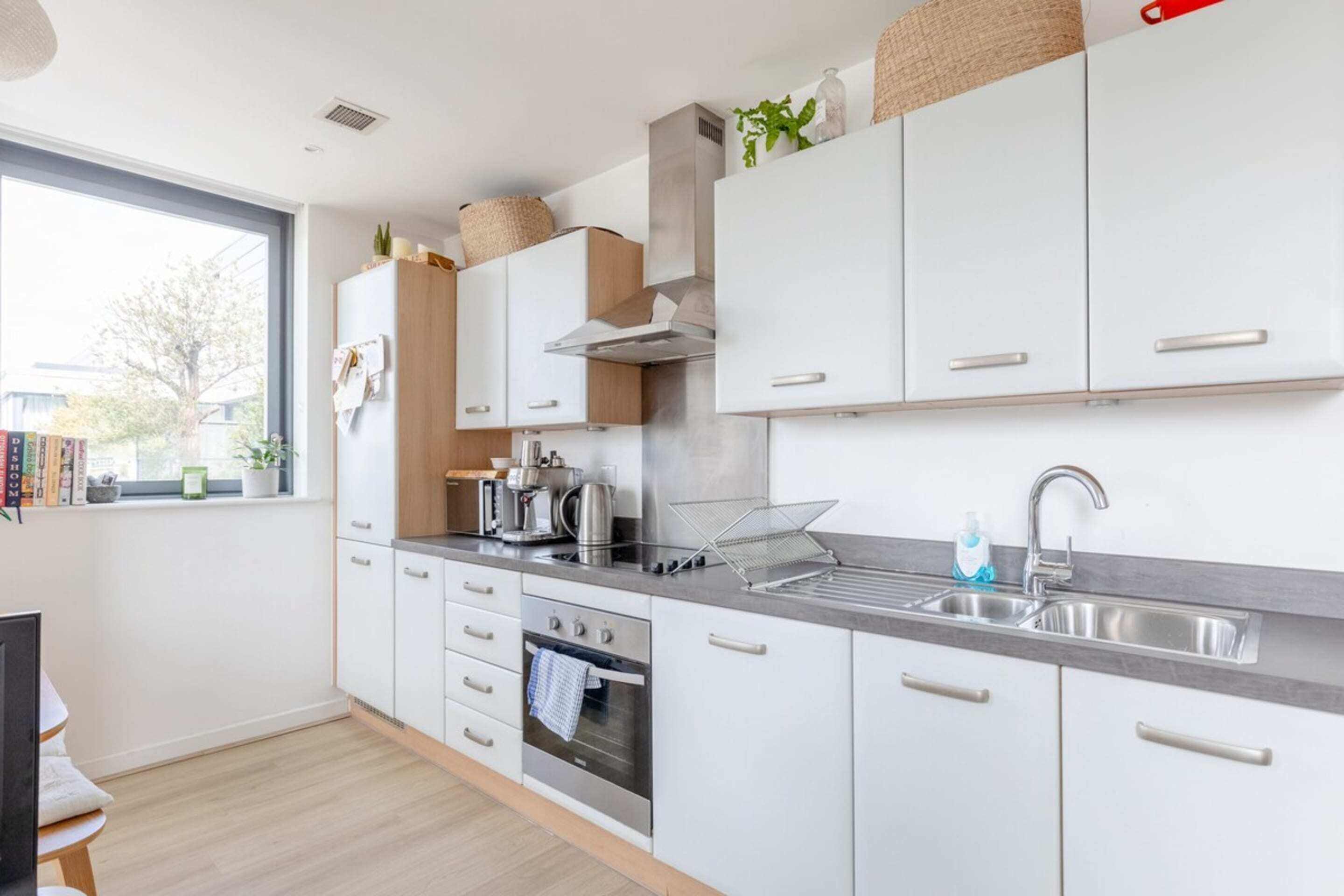 A modern kitchen with white cabinets, stainless steel appliances, and a grey countertop.