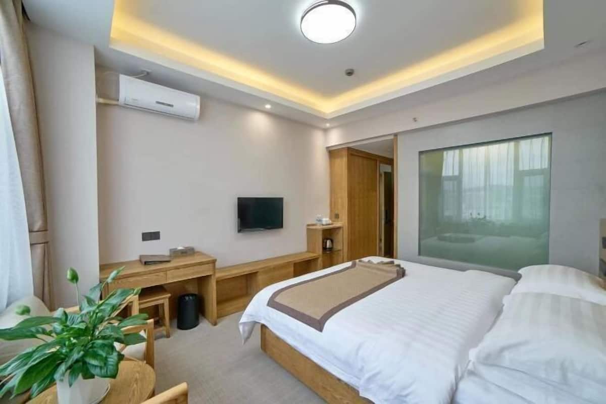 Ein Hotelzimmer mit Bett, Schreibtisch, Fernseher und einem großen Fenster.