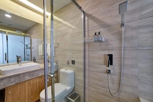 Un baño moderno con ducha de vidrio, inodoro y lavabo con tocador de madera.
