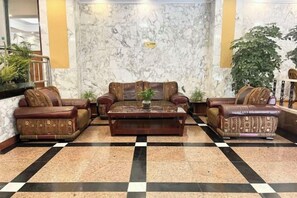 A lobby with a checkered floor, two sofas, a coffee table, and a large potted plant. - Landu shuntian Hotel (Baoshan)