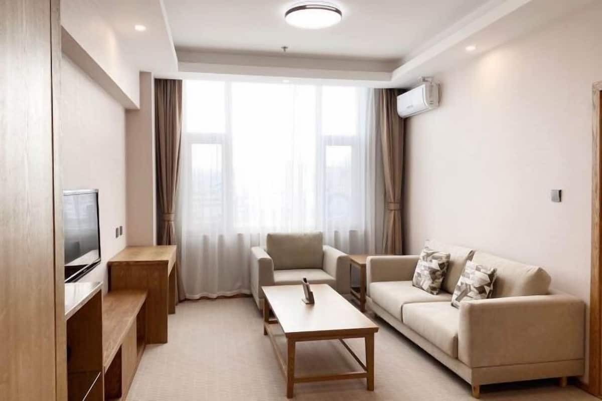 Ein modernes Wohnzimmer mit Flachbildfernseher, Holzmöbeln, einer Couch und einem Couchtisch.