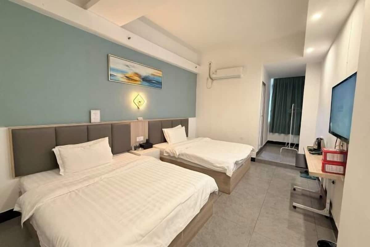 A hotel room with two beds, a desk, a TV, and a painting on the wall.