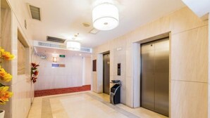 A hotel lobby with a marble floor, a reception desk, a trash bin, and two elevators. - Haolaiwan Hotel (Luoding)
