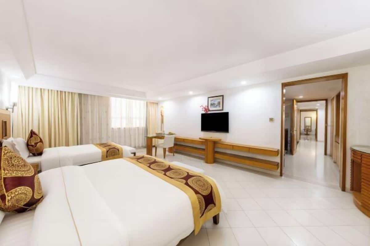 A hotel room with two beds, a TV, a desk, and a bathroom visible through an open door.
