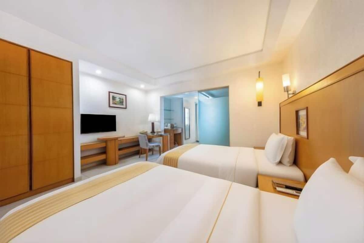 A hotel room with two beds, a desk, a TV, and a wardrobe.