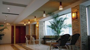 A hotel lobby with a reception desk, seating area, and a large window with a view. - Haolaiwan Hotel (Luoding)