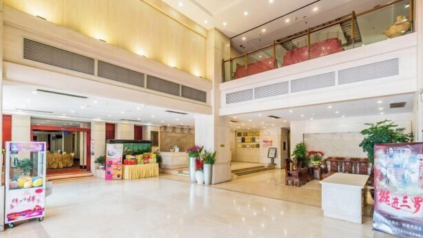 A spacious lobby with a high ceiling, a reception desk, and a staircase leading to an upper level. - Haolaiwan Hotel (Luoding)