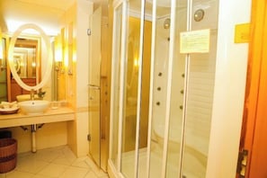 A bathroom with a large mirror, a sink, a glass-enclosed shower, and a toilet. - Haolaiwan Hotel (Luoding)