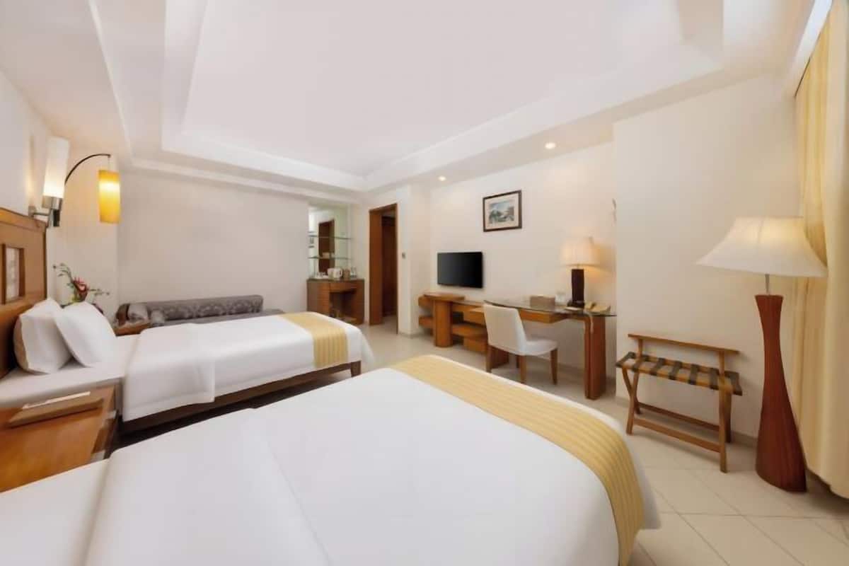 A hotel room with two beds, a desk, a chair, a TV, and a lamp.