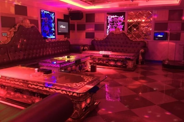A room with a checkered floor, two ornate sofas, a glass coffee table, and decorative screens with floral designs. - Haolaiwan Hotel (Luoding)