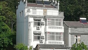 A multi-story building with traditional architectural features, including a balcony and solar panels on the roof. - Qingliangzhai Liu Yinong Family Lodging (Wuhan)